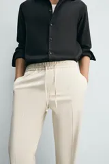 Pantalón regular fit color negro de tejido con viscosa, con cintura elástica ajustable con cordón, bolsillos frontales y traseros.