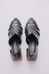 Sandalias de cuero negro con talón descubierto, tiras anchas entrecruzadas en el empeine y taco bajo de madera.