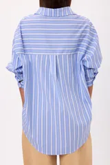 Camisa de corte oversize con diseño de rayas verticales en tonos celeste y blanco, cuello clásico y cierre frontal con botones.