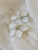 Par de aros colgantes con forma de flor blanca con borde plateado y centro de perlas y cuentas plateadas.