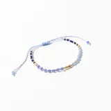 Pulsera de hilo celeste con cuentas de cristal azul y dorado.