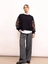 Buzo de algodón color negro con cuello redondo, mangas largas y bordado floral XL en color cobre en las mangas. Presenta un diseño holgado y cómodo.