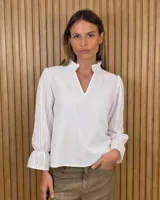Blusa de algodón color azul, de corte suelto, con mangas largas abullonadas y cuello con volados y escote en V.