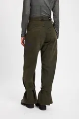 Jean tipo baggy de pierna ancha y recta, color marrón oscuro. Presenta detalles de costuras decorativas, bolsillos laterales redondeados y bolsillos traseros grandes. Incluye tiras ajustables con hebillas metálicas en los tobillos para un efecto fruncido.