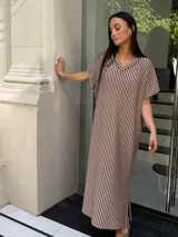 Vestido largo de tejido de punto con diseño de rayas verticales en blanco y negro. Presenta escote en V, mangas cortas y tajos laterales en el ruedo para mayor movimiento.