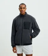 Campera deportiva reversible de manga larga con cierre frontal de cremallera, cuello alto y bolsillos laterales. Confeccionada en poliamida con forro interior de fleece, presenta un pequeño logo estampado en el pecho.