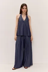 Blusa azul de denim liviano, con escote en V y cuello halter. Cuenta con cierre frontal de botones y diseño suelto de caída fluida.