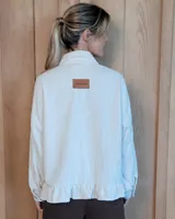 Sobrecamisa de pana color marrón oscuro, con cuello camisero, cierre frontal de botones y detalle de volado en el ruedo. Presenta mangas largas con puños y bolsillos frontales aplicados.