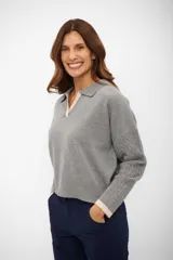 Suéter de tejido de punto color gris, con cuello polo y escote en V ribeteado en color beige. Mangas largas con trenzas en relieve y puños ribeteados en color beige.