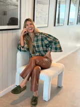 Camisa de color marrón oscuro con cuello clásico y mangas abullonadas con puños elásticos. Presenta un corte holgado y cierre frontal con botones.