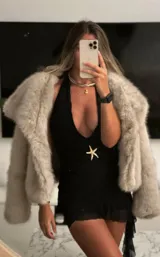 Minivestido negro con escote halter pronunciado, detalle de estrella de mar dorada en la cintura, falda drapeada y ruedo irregular con volados de tul.