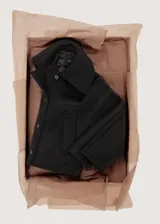 Chaqueta negra de corte corto y holgado, confeccionada con mezcla de lana. Cuenta con cuello ancho y solapa de piel sintética en tono beige claro, cierre frontal con botones oscuros y mangas largas amplias.