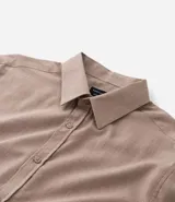 Camisa de manga larga confeccionada en tricolina de algodón, con cuello inglés, cierre frontal de botones y puños abotonados. Diseño liso y versátil.