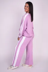 Pantalón deportivo de algodón color lila con franjas blancas laterales, cintura elástica y corte holgado de pierna ancha.