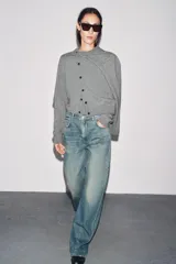 Chaqueta de tejido de punto color verde musgo, de corte cropped, con cuello redondo y cierre frontal de botones oscuros.