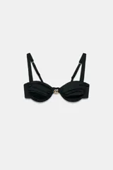 Top de bikini con aros y escote corazón, color negro, con detalle de aplicación metálica combinada en el centro del pecho. Tirantes finos ajustables.