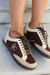 Championes de estilo urbano en combinación de tonos marrones y crema, confeccionados en gamuza y cuero. Presentan cordones jaspeados, suela de goma y detalle de logo bordado en el lateral.
