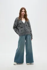 Cardigan de punto gris con estampado de estrellas negras, cuello en V, cierre frontal con botones y mangas largas con puños acanalados.