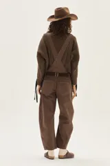 Overol de jean color marrón con calce barrel, tiro medio, pierna ancha y redondeada que termina a la altura del tobillo.