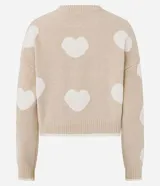 Suéter de punto con cuello redondo y sisa desplazada, de corte corto y ajuste slim. Presenta un diseño estampado con corazones en contraste sobre fondo beige.