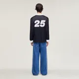 Camiseta Adidas de manga larga en colaboración con la banda Oasis, de color negro con cuello polo, puños y detalles en blanco marfil. Presenta las tres tiras características en las mangas, el logo trébol de Adidas, un escudo circular conmemorativo de la gira 'Live '25' y el estampado con la inscripción 'oasis' en el centro del pecho.