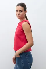 Blusa sin mangas color rojo, con cuello redondo y detalle de drapeado en los hombros. Presenta un corte recto y holgado.