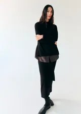 Falda midi negra de punto, de corte recto y tiro alto, con detalle de lazo ajustable en la cintura.