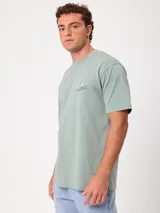 Remera negra de ajuste holgado con gran estampado gráfico en la espalda de temática tropical con una playa, palmeras y la inscripción "Welcome to Surfers Paradise".