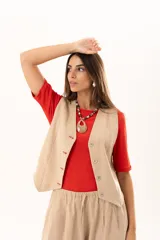 Chaleco de corte sastre en color beige, con escote en V, cierre frontal mediante botones y costuras decorativas en contraste.