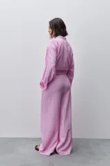 Pantalón de tiro alto con silueta amplia y caída fluida, confeccionado en tejido celeste con textura a rayas finas. Cuenta con cintura elástica con lazo de ajuste y bolsillos laterales.