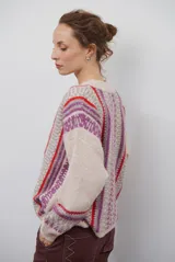 Cardigan de punto con escote en V y cierre frontal de botones. Presenta un diseño estampado con patrones geométricos en tonos beige, marrón y detalles en azul vibrante.