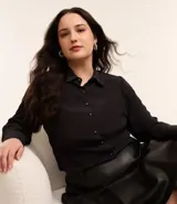 Camisa negra de crepé con cuello inglés, mangas largas y abotonadura frontal. Corte clásico y elegante.