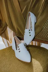 Chatitas negras de cuero con punta fina y apliques de tachas doradas.