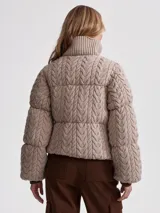 Campera puffer beige con cuello alto acanalado, cierre frontal con cremallera y bolsillos laterales.