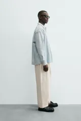 Camisa de denim de algodón, color celeste claro lavado, de corte relajado (relaxed fit) con cuello solapa, manga larga terminada en puño con botón y cierre frontal de botonadura. Presenta un pequeño bordado a contraste en el pecho.