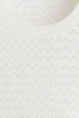 Remera de punto color blanco, con textura de pequeños patrones en relieve, cuello redondo y mangas cortas.