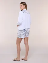 Campera liviana de lino color blanco, con estilo denim y silueta semi entallada. Presenta un canesú superior estampado con motivos florales en tonos azules y tostados, cuello camisero, abotonadura frontal con botones rústicos y bolsillos con solapa en el pecho.