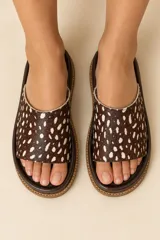 Sandalias de cuero vacuno con plataforma baja, capellada ancha de pelo con estampado animal print tipo dálmata en tonos marrón oscuro y blanco, y plantilla marrón.
