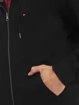 Buzo negro con capucha, cierre de cremallera, bolsillos laterales y logo de Tommy Hilfiger bordado en el pecho.