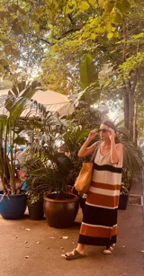 Vestido largo tejido a rayas horizontales en tonos crudo, tostado y negro, con breteles finos y abertura lateral.