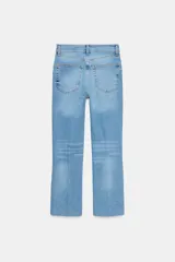 Jeans de mezclilla azul claro, tiro medio, corte recto y ligeramente acampanado en el bajo. Presenta cinco bolsillos y cierre frontal con cremallera y botón metálico.