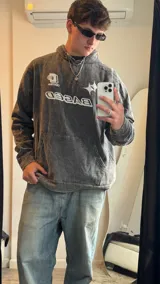 Buzo gris nevado con capucha y bolsillo tipo canguro. Estampado frontal con la palabra "BASED" y un logo.