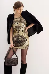 Vestido corto de lentejuelas doradas con diseño estampado de corazones y motivos ornamentales en tonos oscuros. Presenta un corte recto y sin mangas.