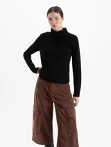 Sweater de lana merino color negro, con cuello medio alto y detalle de frunces en los hombros que aportan volumen. De calce regular y tejido suave.
