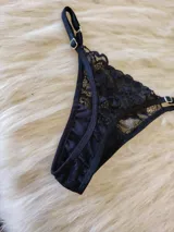 Conjunto de lencería compuesto por un bralette de encaje negro con breteles regulables y una tanga regulable con corte cola less y entrepierna de algodón.