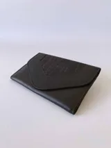 Billetera de cuero negro con diseño de solapa en forma de V y textura combinada de cuero liso y efecto croco. Cuenta con cierre mediante broche a presión.