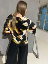 Blusa de manga larga acampanada con estampado abstracto en tonos negro, blanco, verde lima y caramelo, de corte holgado.