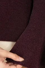 Suéter de punto color púrpura con cuello perkins, manga larga y puños acampanados. Presenta una textura sutil con acabado brillante.