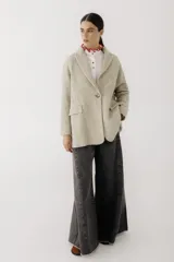 Blazer de corte recto y holgado en color beige con textura de espiga. Presenta solapas clásicas, cierre frontal con un botón central y bolsillos laterales con solapa.
