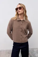 Cardigan de punto color taupe con cuello polo y cierre frontal de botones. Presenta mangas largas con puños ajustados y un corte recto a la altura de la cintura.